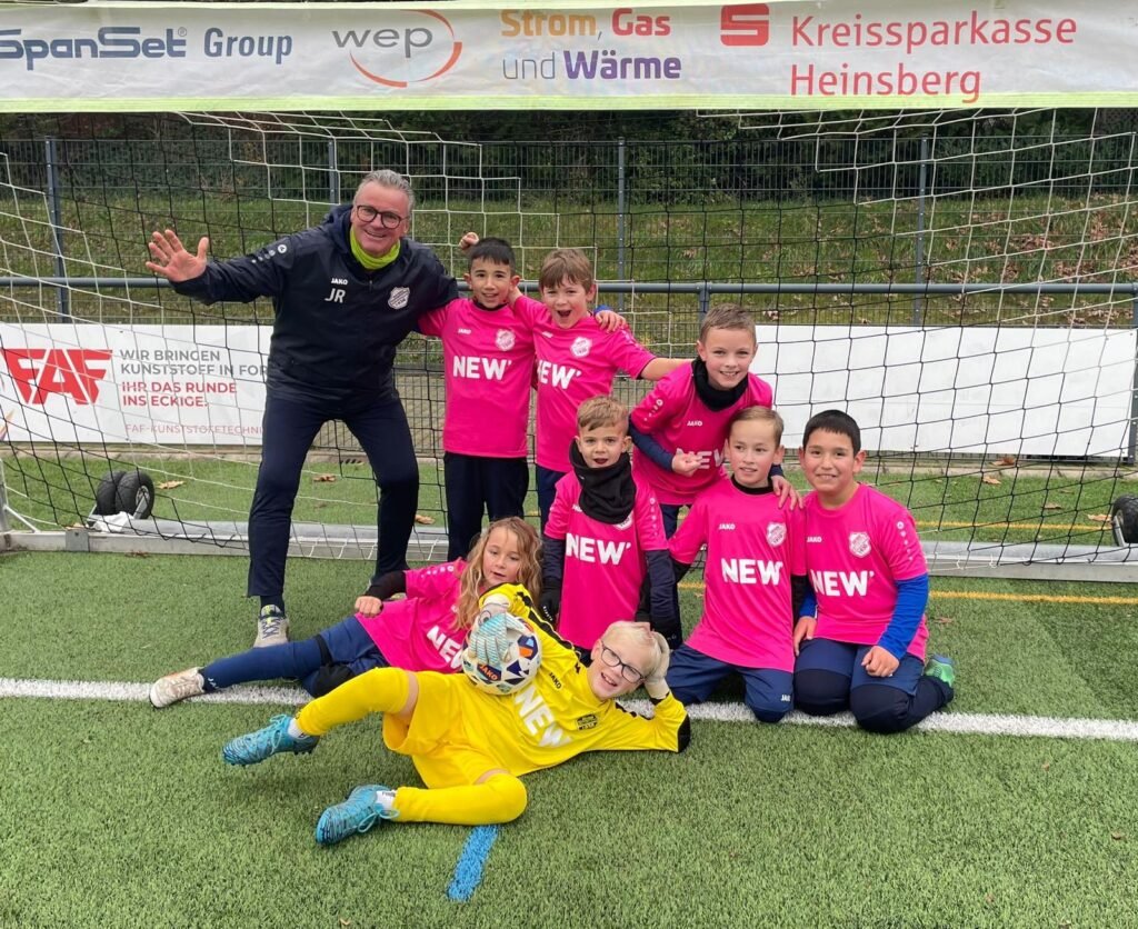 E-Junioren in pinken Trikots mit ihrem Trainer vor dem Tor beim Turnier
